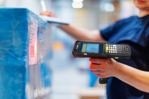 Worker scans a blue pallet with a handheld barcode scanner in a warehouse.